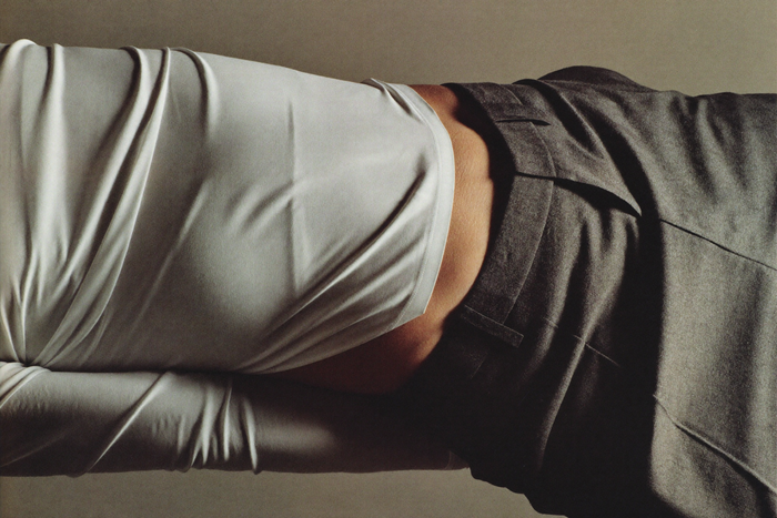 Man in fitted shirt, flat stomach line, profile view, tailored trousers