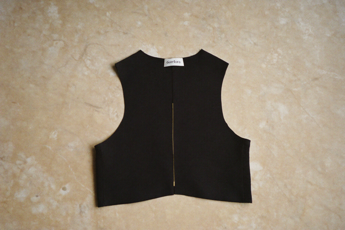 Compression vest folded on bone marble surface, gold thread detail