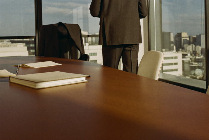Man at office meeting, posture upright at 4pm, jacket on chair behind