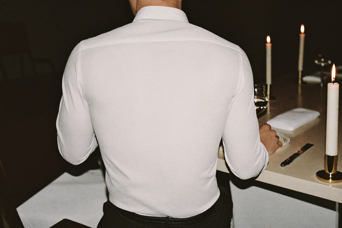 Man in dress shirt at restaurant table, evening, posture composed
