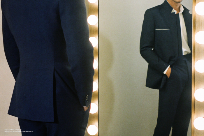 Profile of man in suit standing in front of mirror, jacket draping cleanly
