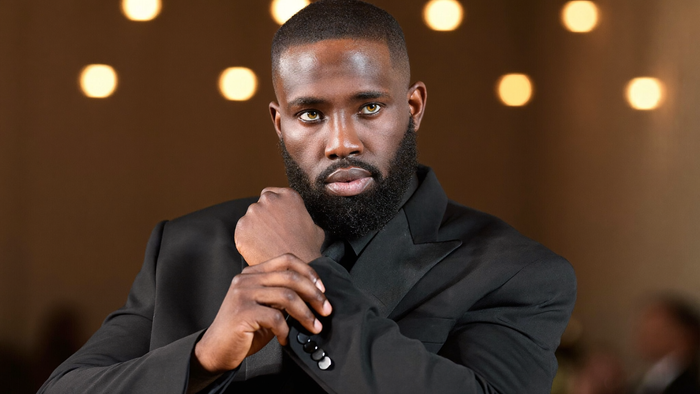 A man adjusting a tailored suit jacket at a formal event, representing UNDR's support for big days