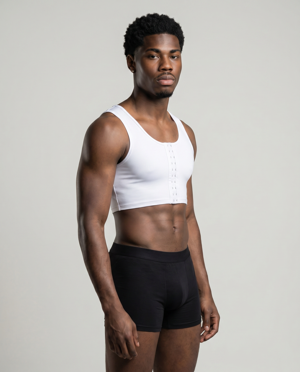 Man wearing a white crop top and black underwear on a plain background
