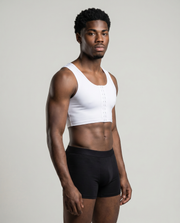 Man wearing a white crop top and black underwear on a plain background