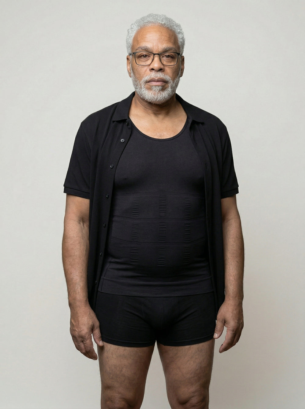 Man wearing a black shirt and black underwear against a plain background