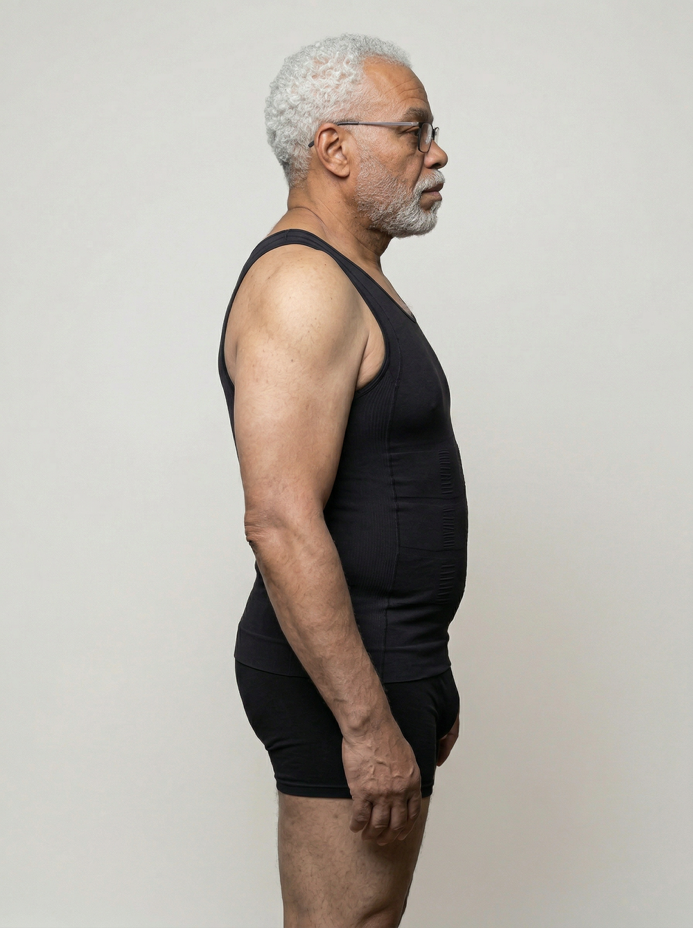 Man wearing a black tank top and shorts against a plain background