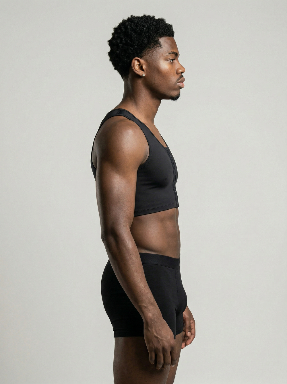 Man wearing a black sports bra and shorts on a light gray background