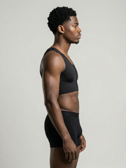 Man wearing a black sports bra and shorts on a light gray background