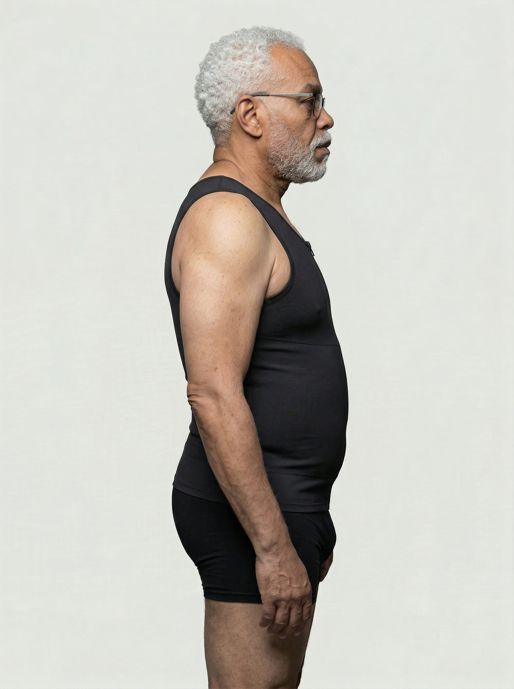 Man wearing a black tank top and shorts against a plain background