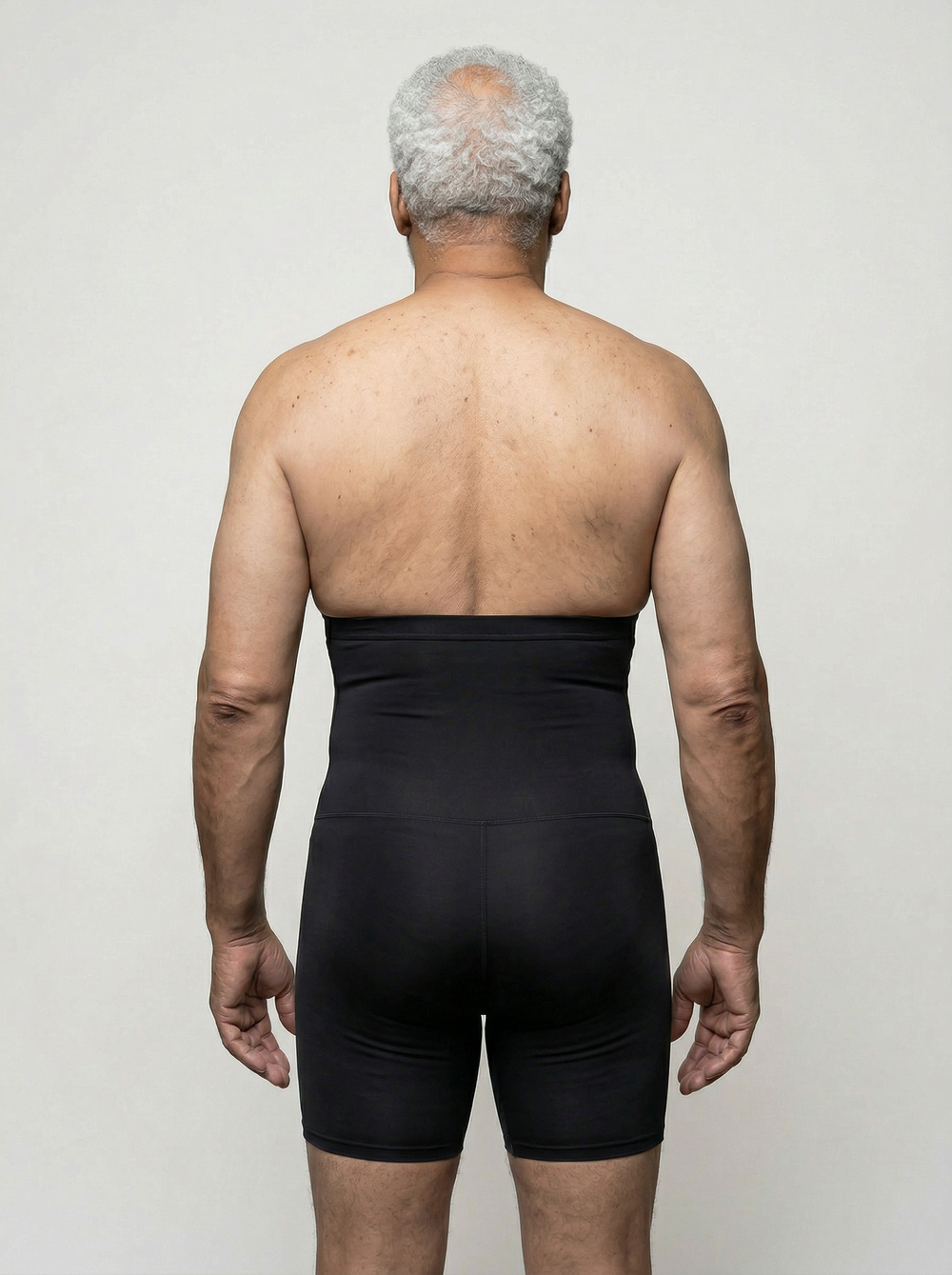 Man wearing a black compression garment against a plain background