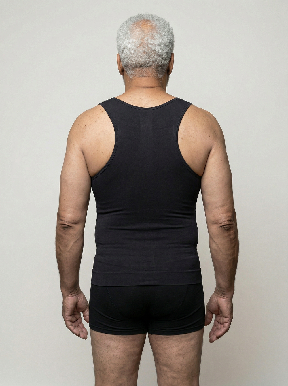 Man wearing a black tank top and shorts against a plain background