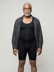 Man wearing a black bodysuit with a gray jacket over it on a plain background