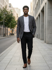 Man in gray blazer and black pants walking on a city street.