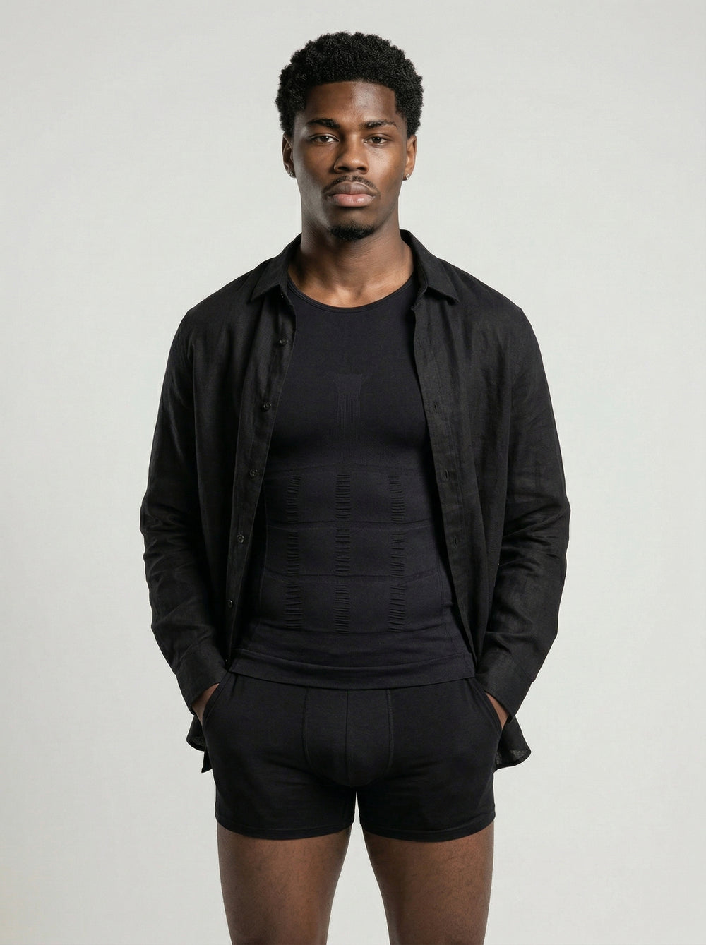 Man wearing a black shirt, black pants, and black shorts against a light gray background