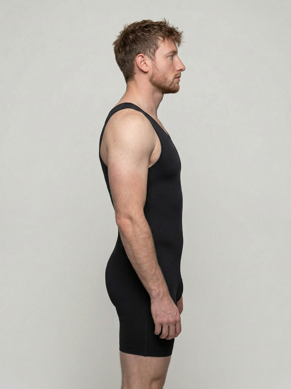 Man wearing a black tank top and shorts against a plain background