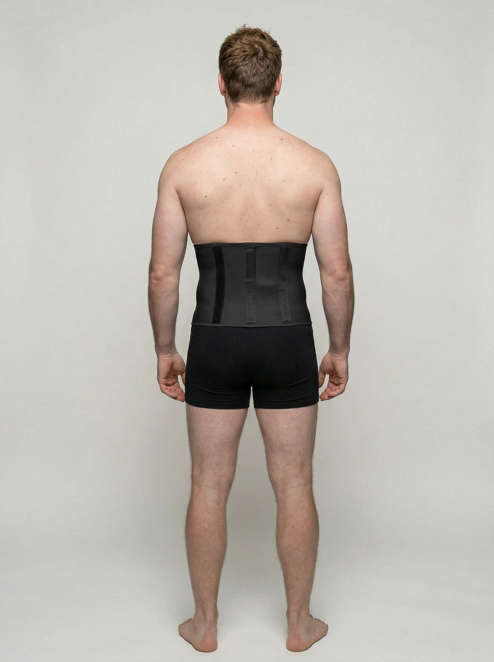 Man wearing a black compression garment on a plain background