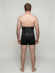 Man wearing a black compression garment on a plain background