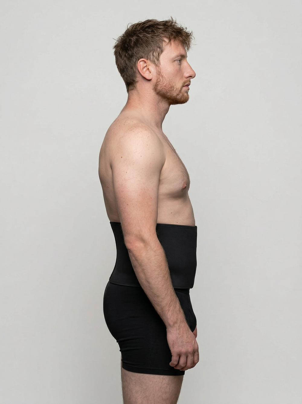 Man wearing a black compression garment against a plain background