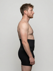 Man wearing a black compression garment against a plain background