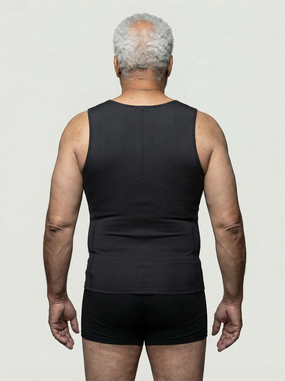 Man wearing a black tank top and shorts on a plain background